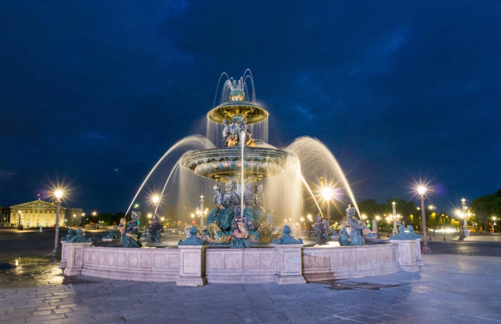 Lit-up view of Fontaine des Mers at Place de la Concorde, Paris at night.