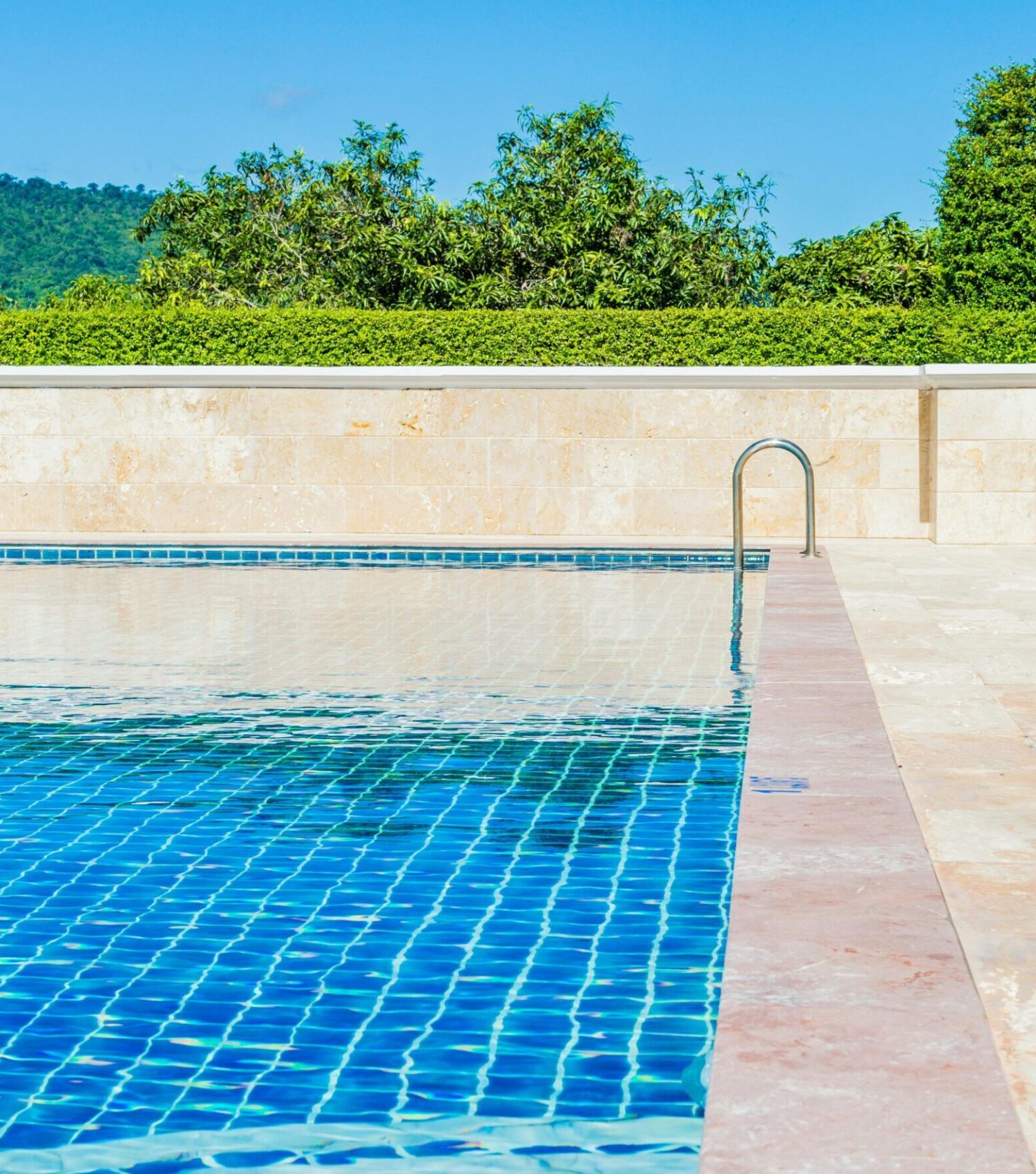 Bright and tranquil poolside scene, capturing a turquoise swimming pool under a clear blue sky.